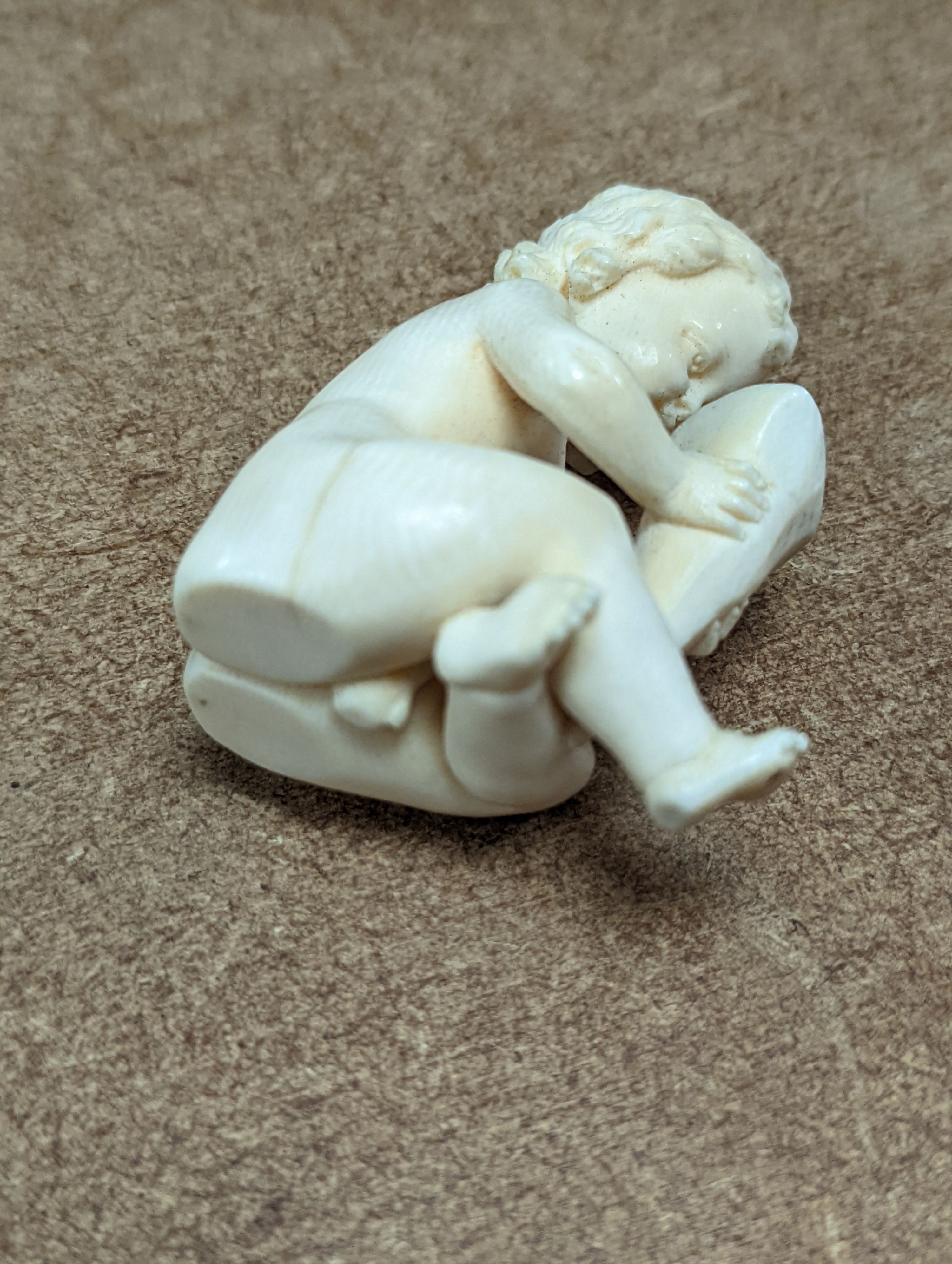 A 19th century Continental carved ivory figure of a child holding a cornucopia - 7cm tall